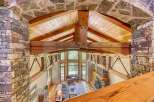 Experience rustic luxury in this stunning great room, featuring a soaring vaulted ceiling with exposed wooden beams and a magnificent stone fireplace.