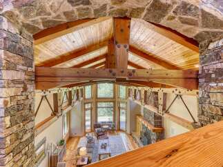 Experience rustic luxury in this stunning great room, featuring a soaring vaulted ceiling with exposed wooden beams and a magnificent stone fireplace.