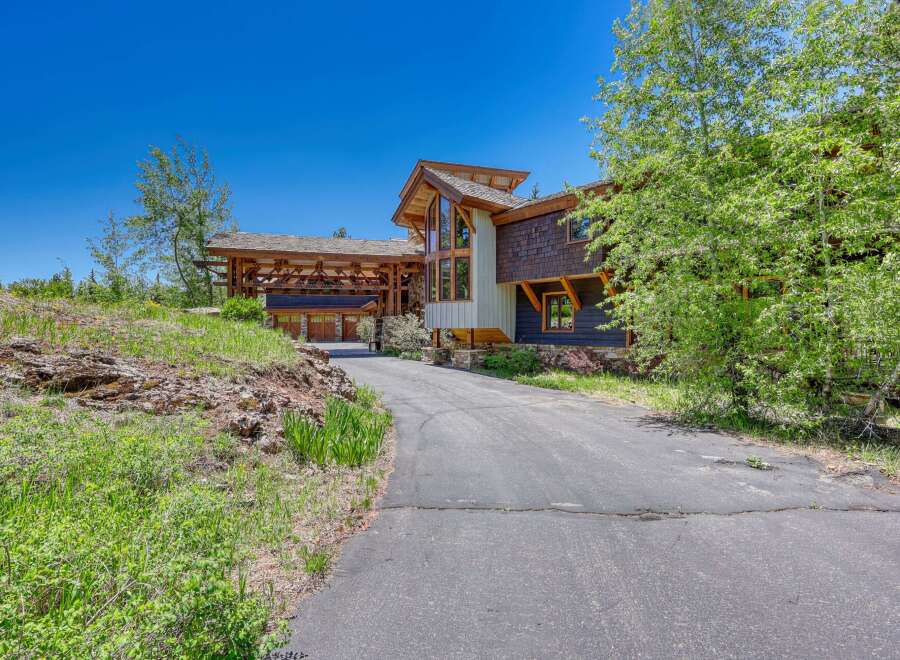 Discover this stunning mountain home featuring a unique architectural design with natural wood accents and a grand covered entryway.