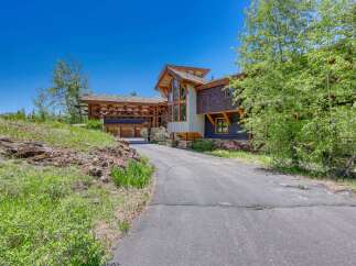 Discover this stunning mountain home featuring a unique architectural design with natural wood accents and a grand covered entryway.