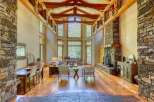 Experience rustic elegance in this stunning living space, featuring a grand stone fireplace and soaring vaulted ceilings with exposed wooden beams.