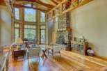Experience breathtaking mountain views from this stunning living room, featuring a grand stone fireplace and soaring wooden beams.