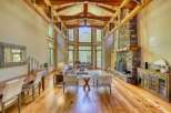 Experience breathtaking mountain views from this stunning living room, featuring a grand stone fireplace and soaring vaulted ceilings with exposed wooden beams.