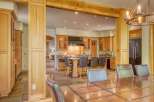 Experience luxury living in this stunning kitchen and dining area, featuring rich wood cabinetry, a spacious island with bar seating, and a grand chandelier.