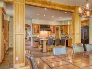 Experience luxury living in this stunning kitchen and dining area, featuring rich wood cabinetry, a spacious island with bar seating, and a grand chandelier.