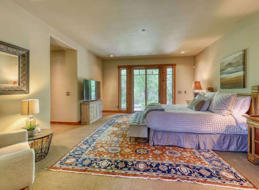Experience ultimate comfort in this luxurious master bedroom, featuring a plush king-sized bed adorned with soft linens and a collection of decorative pillows.