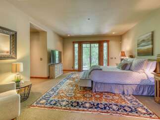 Experience ultimate comfort in this luxurious master bedroom, featuring a plush king-sized bed adorned with soft linens and a collection of decorative pillows.