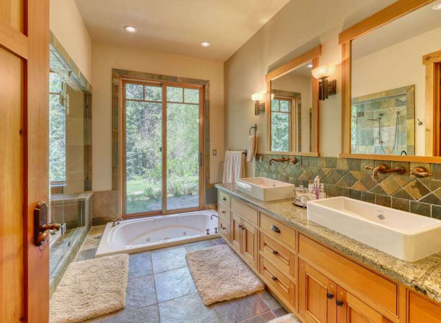 Experience luxury in this stunning bathroom featuring a deep soaking tub with a view of the lush outdoors.