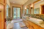 Experience luxury in this stunning bathroom featuring a deep soaking tub with a view of the lush outdoors.