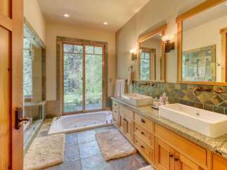 Experience luxury in this stunning bathroom featuring a deep soaking tub with a view of the lush outdoors.
