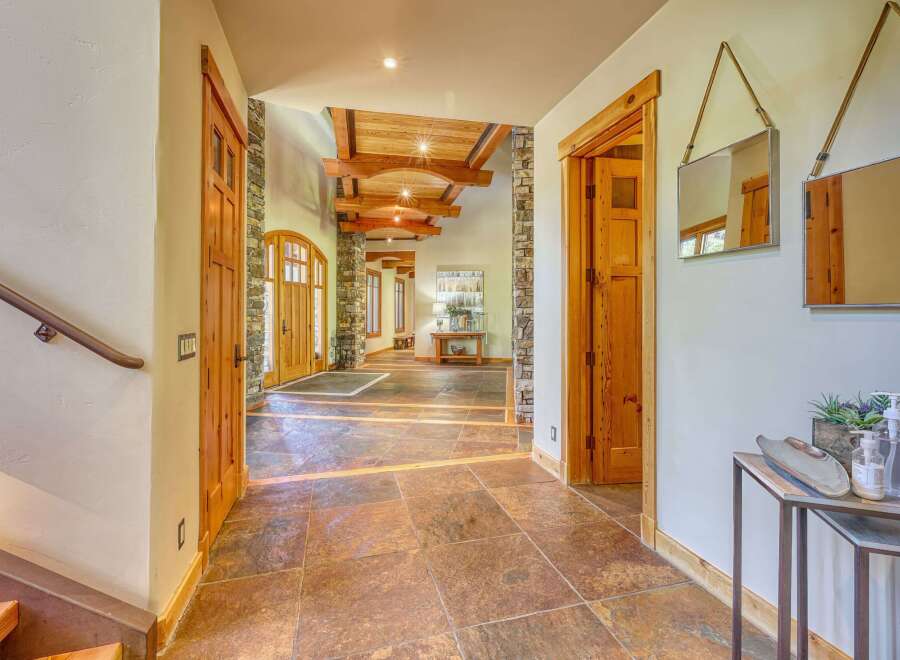 Step into this grand entryway featuring stunning natural stone flooring and exposed wooden beams on the ceiling.