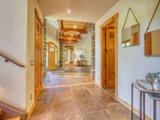 Step into this grand entryway featuring stunning natural stone flooring and exposed wooden beams on the ceiling.
