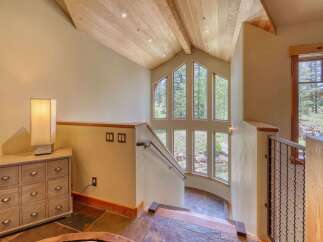 Ascend to new heights in this stunning home, featuring a dramatic vaulted ceiling with exposed wooden beams and recessed lighting.
