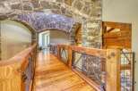 Experience rustic elegance in this stunning home featuring a unique stone archway leading to a charming wooden bridge.