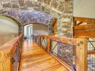Experience rustic elegance in this stunning home featuring a unique stone archway leading to a charming wooden bridge.