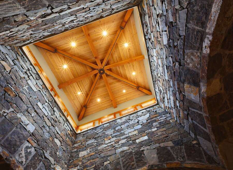 Experience rustic elegance with this stunning architectural design, featuring a dramatic stone-clad atrium that opens to a beautifully crafted wooden ceiling.