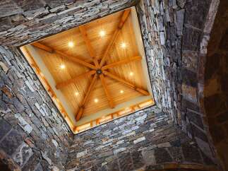 Experience rustic elegance with this stunning architectural design, featuring a dramatic stone-clad atrium that opens to a beautifully crafted wooden ceiling.