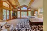 Experience luxury mountain living in this stunning bedroom featuring vaulted wood-beamed ceilings and expansive windows that flood the space with natural light.