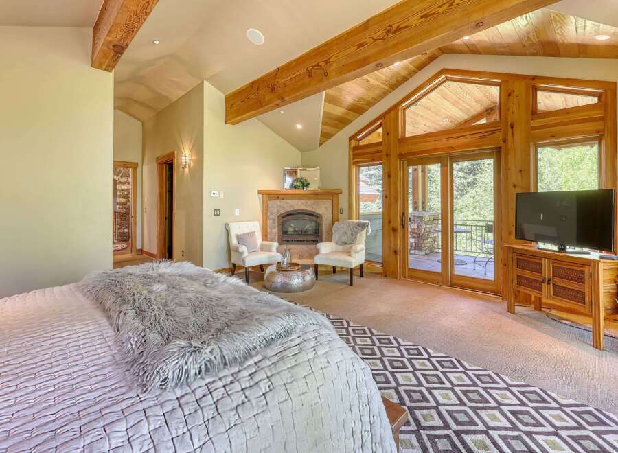 Experience luxury mountain living in this stunning bedroom featuring a cozy fireplace and direct access to a private balcony with scenic views.