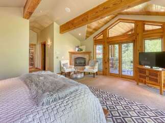 Experience luxury mountain living in this stunning bedroom featuring a cozy fireplace and direct access to a private balcony with scenic views.