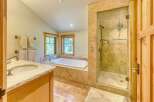 Experience luxury in this spacious bathroom featuring a deep soaking tub and a separate glass-enclosed shower with elegant tilework.