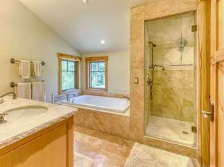 Experience luxury in this spacious bathroom featuring a deep soaking tub and a separate glass-enclosed shower with elegant tilework.