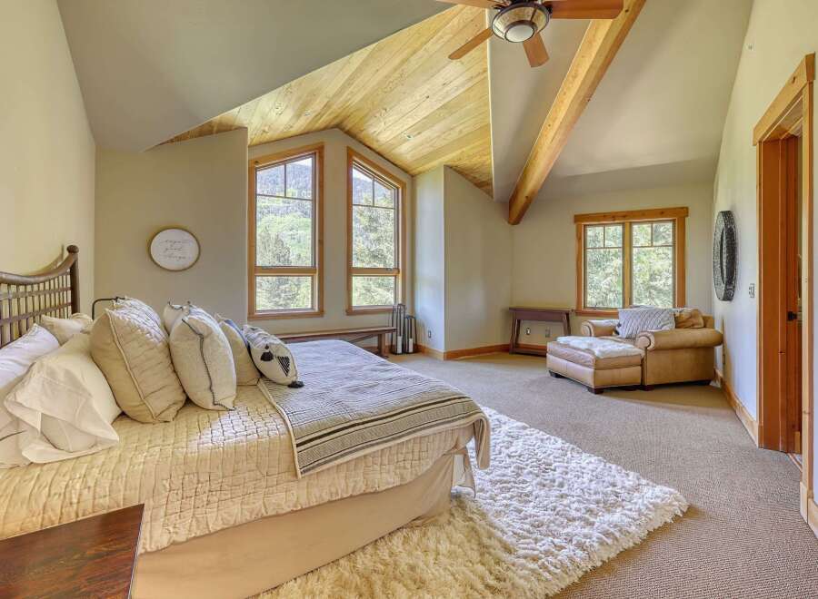 Experience rustic charm in this inviting bedroom, featuring a cozy bed adorned with plush pillows and a textured quilt.
