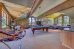 This spacious attic game room offers a perfect blend of entertainment and relaxation, featuring a pool table, arcade games, and multiple beds for guests.