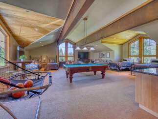 This spacious attic game room offers a perfect blend of entertainment and relaxation, featuring a pool table, arcade games, and multiple beds for guests.