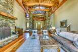 Experience rustic elegance in this grand living room, featuring a magnificent stone fireplace and soaring wooden beam ceilings.