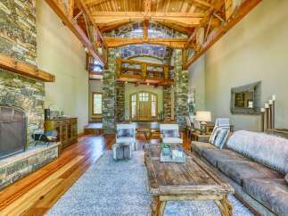 Experience rustic elegance in this grand living room, featuring a magnificent stone fireplace and soaring wooden beam ceilings.
