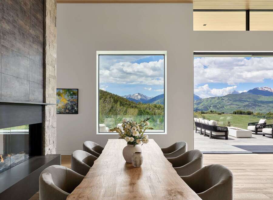 Experience luxurious mountain living in this stunning dining room, featuring a live-edge wood table and plush upholstered chairs.