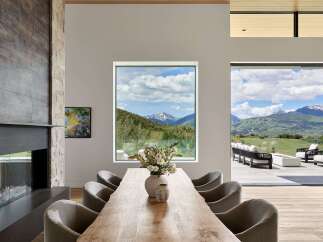 Experience luxurious mountain living in this stunning dining room, featuring a live-edge wood table and plush upholstered chairs.