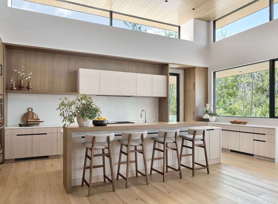 Experience modern luxury in this stunning kitchen, featuring a spacious island with comfortable bar seating and sleek, light wood cabinetry.