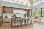 Experience modern luxury in this stunning kitchen, featuring a spacious island with comfortable bar seating and sleek, light wood cabinetry.