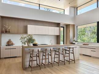 Experience modern luxury in this stunning kitchen, featuring a spacious island with comfortable bar seating and sleek, light wood cabinetry.