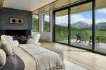 Experience luxury mountain living in this stunning bedroom featuring a modern fireplace and expansive sliding glass doors that open to breathtaking panoramic views.