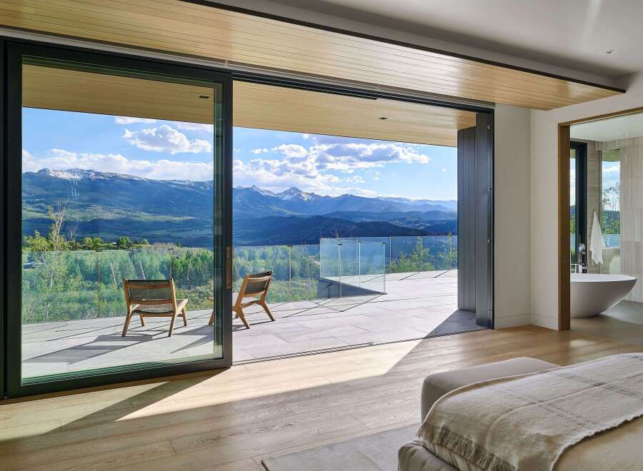 Experience breathtaking mountain views from this luxurious master suite, featuring expansive sliding glass doors that open to a private balcony.
