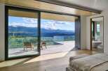 Experience breathtaking mountain views from this luxurious master suite, featuring expansive sliding glass doors that open to a private balcony.