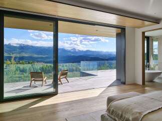 Experience breathtaking mountain views from this luxurious master suite, featuring expansive sliding glass doors that open to a private balcony.