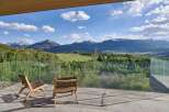 Experience breathtaking mountain views from this stunning modern home, featuring a spacious balcony with comfortable seating.