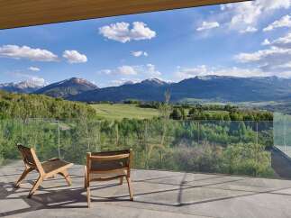Experience breathtaking mountain views from this stunning modern home, featuring a spacious balcony with comfortable seating.