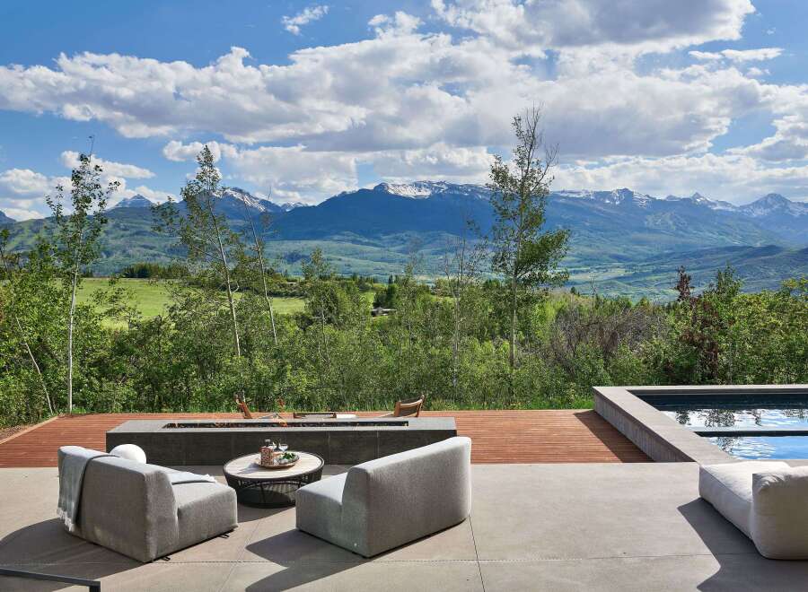 Experience breathtaking mountain views from this luxurious outdoor living space, complete with a modern fire pit and comfortable seating.