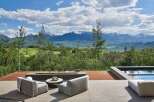 Experience breathtaking mountain views from this luxurious outdoor living space, complete with a modern fire pit and comfortable seating.