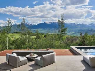 Experience breathtaking mountain views from this luxurious outdoor living space, complete with a modern fire pit and comfortable seating.