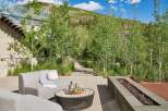 Experience luxury outdoor living with this stunning patio featuring a modern sectional sofa, a stylish coffee table with drinks, and a sleek linear gas fire pit.