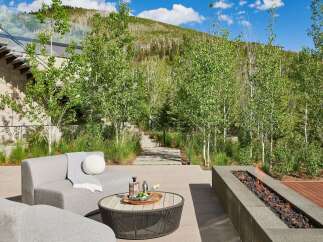 Experience luxury outdoor living with this stunning patio featuring a modern sectional sofa, a stylish coffee table with drinks, and a sleek linear gas fire pit.