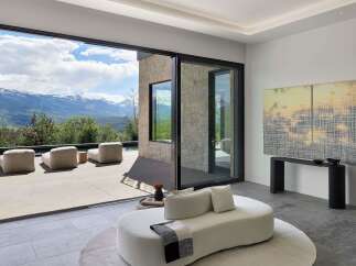 Experience breathtaking mountain views from this luxurious modern living space, featuring expansive sliding glass doors that seamlessly connect indoor and outdoor living.
