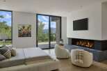 Experience luxury mountain living in this stunning bedroom featuring a modern gas fireplace and a large flat-screen TV.