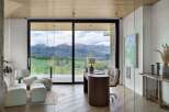 Experience breathtaking mountain views from this modern home office, featuring expansive glass walls and a sleek wooden desk.